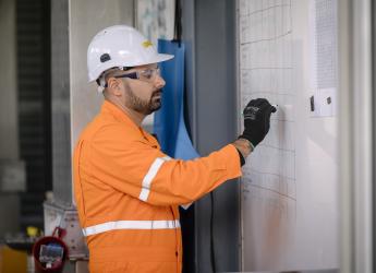 A male production manager, writing on a whiteboard. 