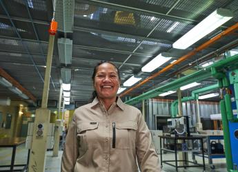 A female manufacturing worker, walking through a workshop. 