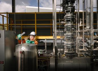 A female engineering production worker, wearing protective workwear and treating chemicals.