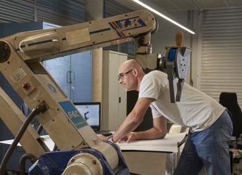 A mechatronics engineer programing an assembly line robot. 