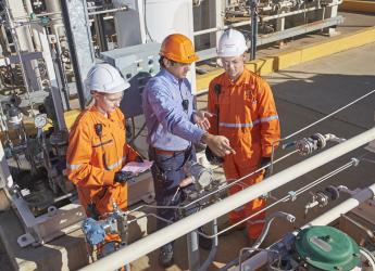 Three engineers observing plant equipment and taking notes. 